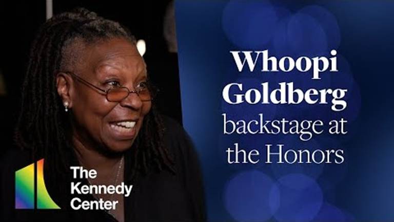 Whoopi Goldberg speaks into an interview microphone backstage at the Honors